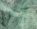 Close-up of greenish-brown stone surface with visible texture.
