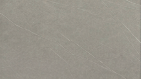 A close-up of a light gray textured surface with subtle diagonal veining and a matte finish.